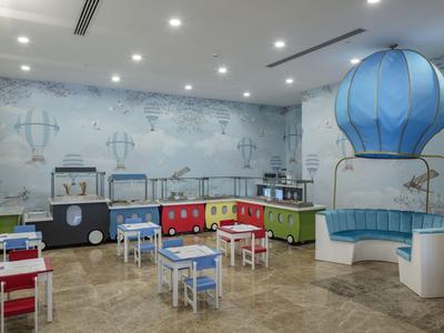 Barevný dětský koutek se stoly, židlemi a velkým balónem uvnitř.