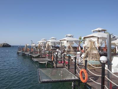 Dřevěné mola s bílými kabinami nad mořem pod jasnou modrou oblohou.