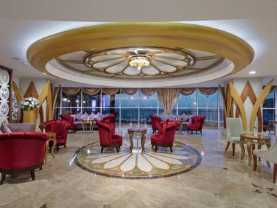 Luxusní hotelový salonek s červenými křesly a velkými okny s výhledem na moře.