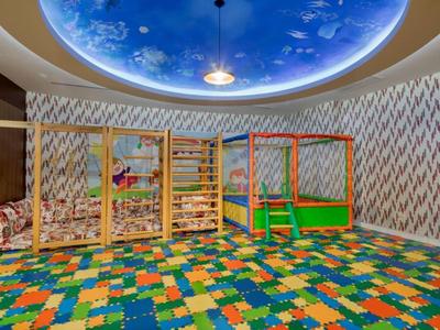 Hotelová herna s barevnou podlahou a stropem zdobeným hvězdnou oblohou.