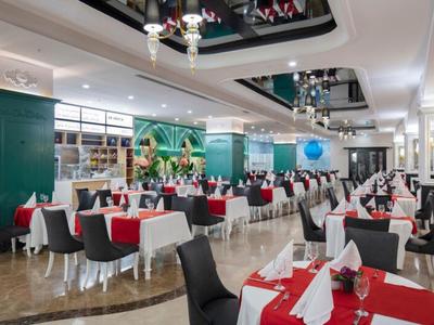 Elegantní jídelna s červenobílými ubrusy, černými židlemi a zelenými stěnami.