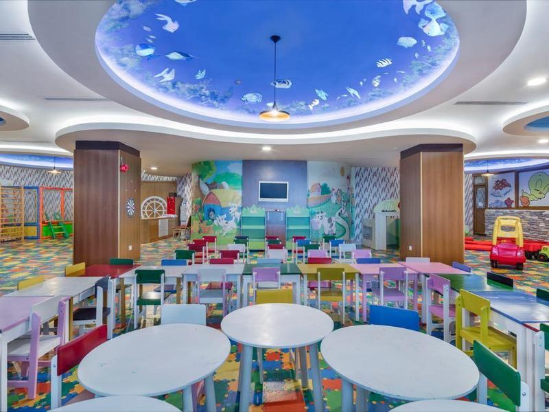 Světla herna pro děti s kulatými stoly a barevnými hrami, moderní zařízení.