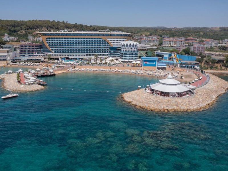 Hotel u moře s pláží, bazénem a průzračnou tyrkysovou vodou.