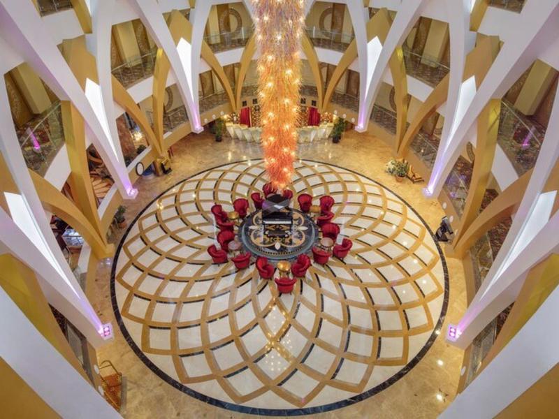 Interiér kulatého hotelového lobby s lustr a elegantní mozaikovou podlahou.