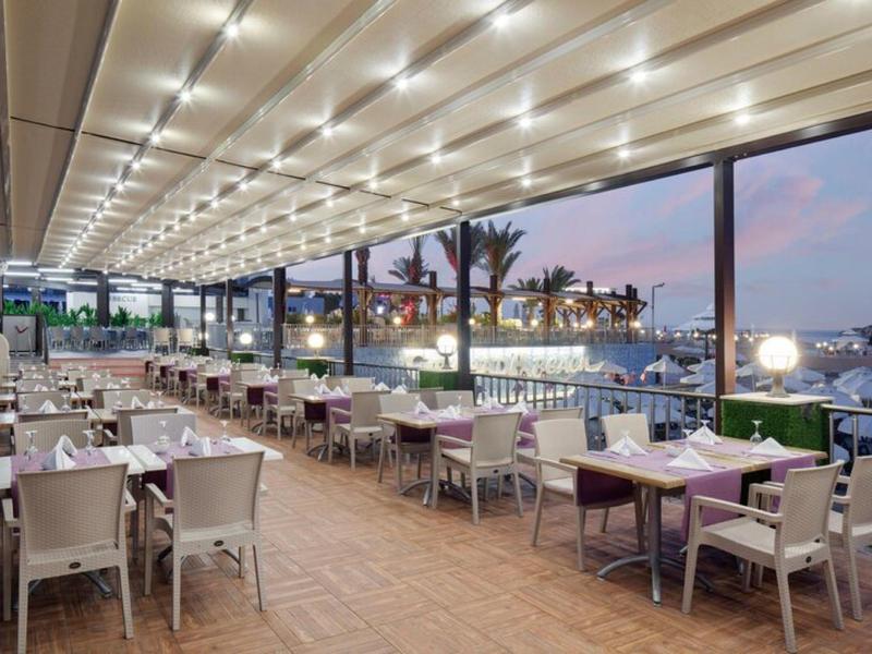 Elegantní restauranční terasa u vody s jemným osvětlením za soumraku.