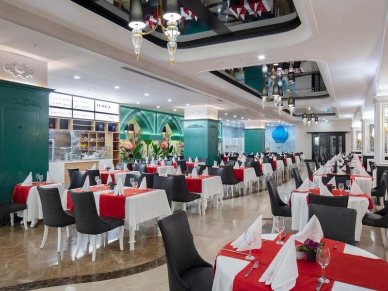 Elegantní jídelna s červenobílými ubrusy, černými židlemi a zelenými stěnami.