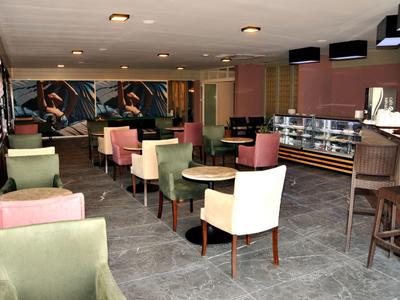 Salle de petit-déjeuner moderne avec des chaises aux couleurs pastel et un buffet en arrière-plan.