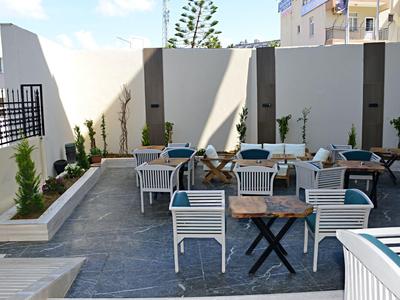 Espace extérieur moderne d'un hôtel avec des chaises blanches et des tables sur une terrasse pavée.