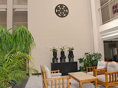 Coin salon confortable avec mobilier en bois et plantes dans une cour d'hôtel lumineuse.