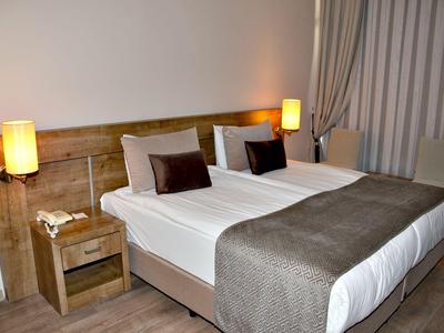 Chambre d'hôtel moderne avec deux lits simples, courtespieds marron et lampes murales.