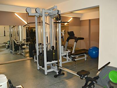 Salle de sport d'hôtel bien éclairée avec machines de musculation et miroir.