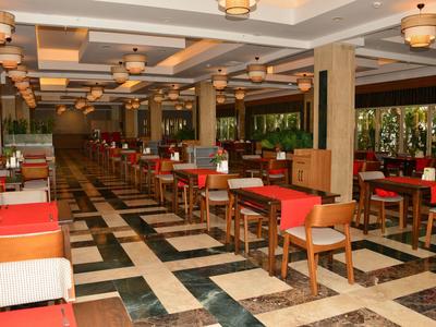 Grand restaurant d'hôtel au design moderne, avec de nombreuses tables et chaises et un éclairage chaleureux.