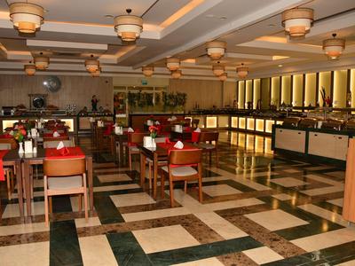 Grande salle à manger élégante avec tables en bois, chaises rouges et vaste espace buffet.