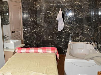 Petit bain d'hôtel avec mur en marbre, baignoire et table de massage avec serviettes.