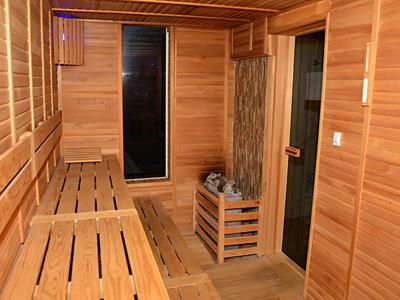 Intérieur de sauna en bois avec bancs, une fenêtre et un poêle de sauna.