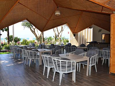 Espace extérieur couvert d'un hôtel avec des tables et chaises blanches en métal.