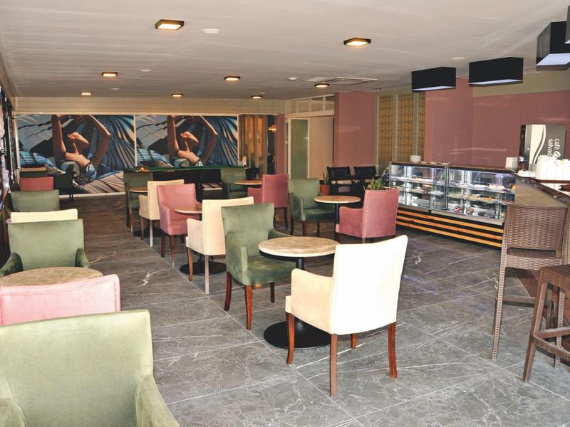 Moderner Frühstücksraum mit bunten Stühlen und Theke in einem Hotel.