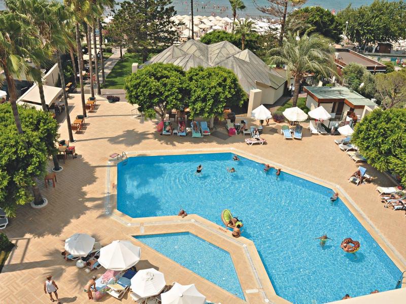Hotelpool mit Liegestühlen, Sonnenschirmen und Palmen in tropischer Umgebung