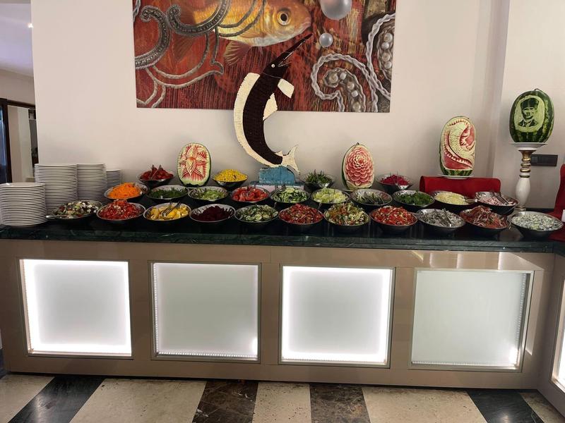 Buffet mit farbenfrohen Früchten, Gemüse, Tellern und dekorativen Wassermelonen.