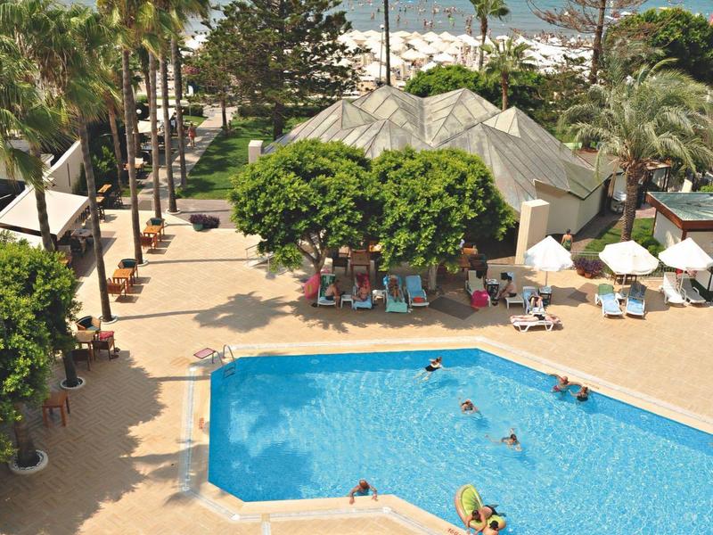 Hotelpool mit Liegestühlen und Blick auf das Meer und Palmen