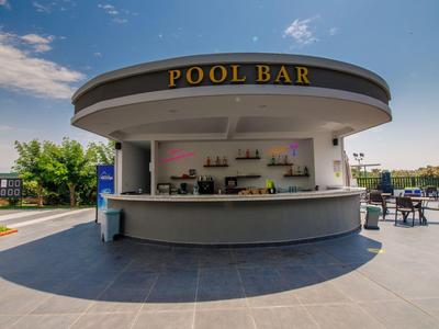 Kruhový bar u bazénu s policemi a sezením pod modrou oblohou