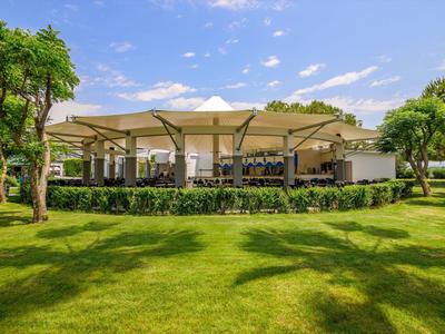 Moderní venkovní pavilon s posezením a stíněním v dobře udržované zahradě.