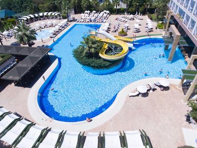 Grande piscina dell'hotel con scivolo d'acqua, lettini e ombrelloni in un ambiente soleggiato.