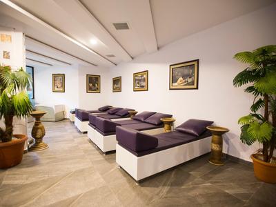 Moderní odpočinková místnost s lehátky, rostlinami a dekorativními obrazy na stěnách.