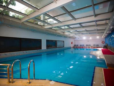 Moderní krytý bazén s čistou vodou a velkými okny v hotelu.