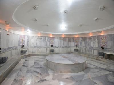 Velká kulatá turecká lázeň s mramorovými plochami a centrálním podiem.