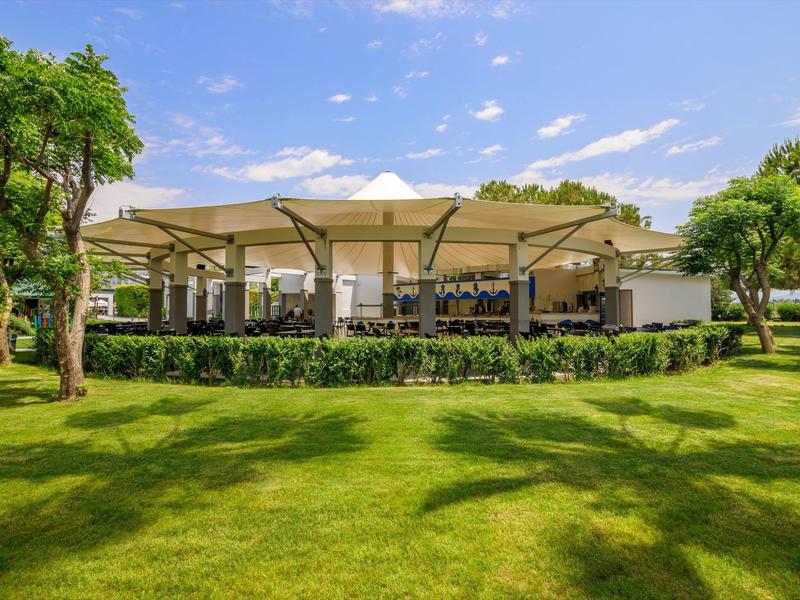 Moderní venkovní pavilon s posezením a stíněním v dobře udržované zahradě.