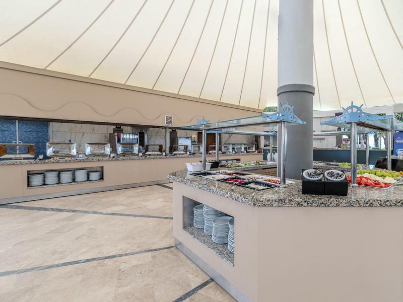 Bufetová část v restauraci s širokým výběrem jídel a talířů.