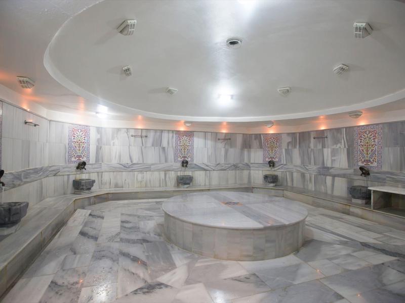 Velká kulatá turecká lázeň s mramorovými plochami a centrálním podiem.