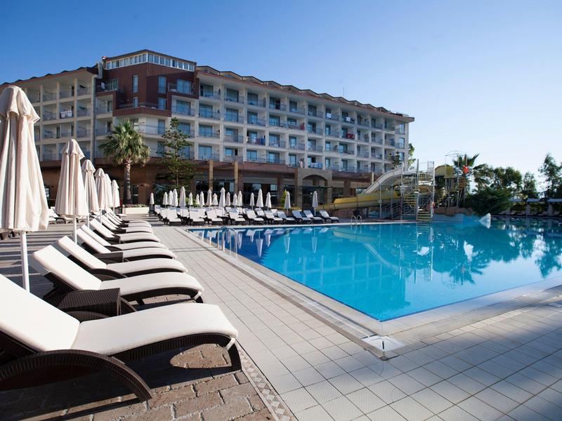 Moderní hotel s velkým venkovním bazénem a lehátky pod jasnou oblohou