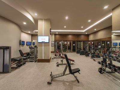 Modern hotel fitness room with various exercise equipment and mirrors on the walls.