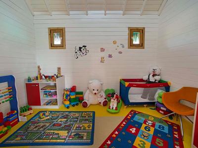 Kleurrijke speelkamer voor kinderen met speelgoed, vloerkleden en twee kleine ramen.