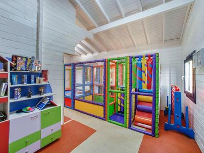 Kleurrijke speelruimte voor kinderen met klimrek en planken in een lichte kamer.