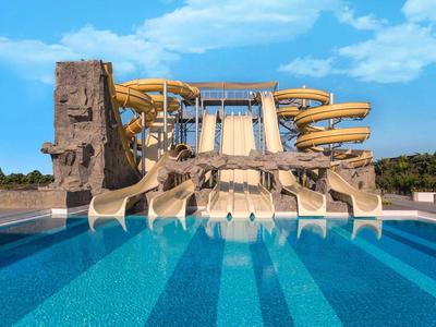 Grote waterglijbaan met meerdere banen naast kunstmatige klimwand voor helder zwembad.