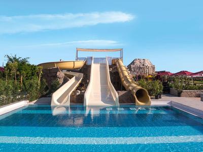Water park with multiple slides leading into a large swimming pool under clear sky.
