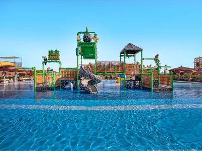 Waterpark met spelletjes en glijbanen in een groot zwembad bij heldere lucht.