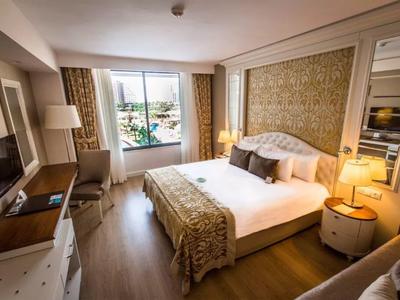 Gezellige hotelkamer met groot bed, houten vloer, raamzicht en warme verlichting.