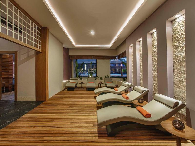 Ontspanningsruimte met comfortabele ligstoelen, zachte verlichting en houtkleurige vloer.