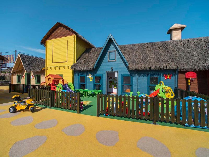 Kleurrijke speeltuinhuizen met hek op zonnige binnenplaats onder blauwe lucht