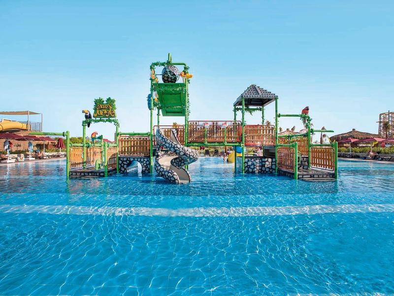 Waterpark met glijbanen en speeltoestellen in een groot zwembad bij helder weer.