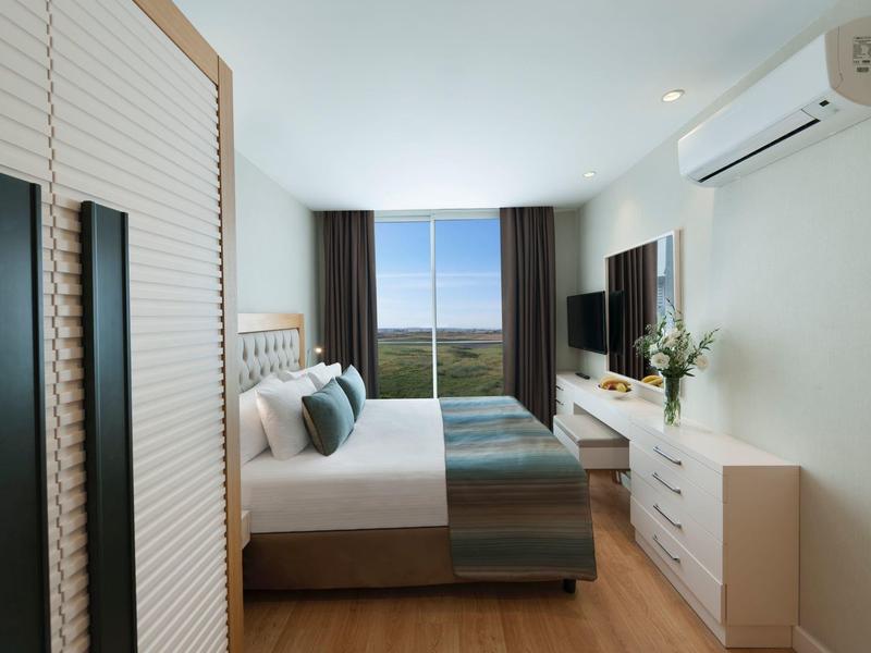 Modern ingericht hotelkamer met tweepersoonsbed, kast en balkon met uitzicht op zee.