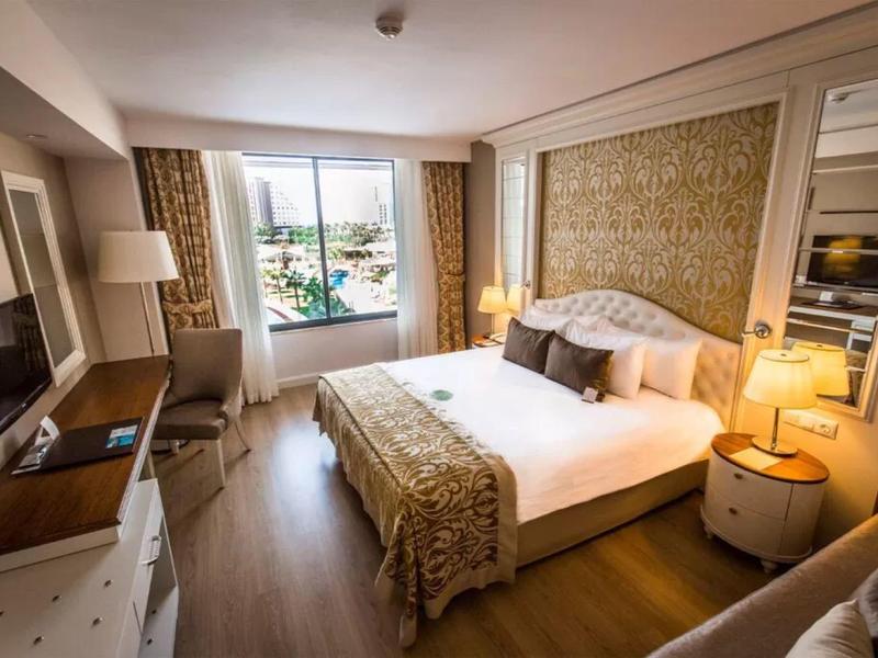 Gezellige hotelkamer met groot bed, houten vloer, raamzicht en warme verlichting.