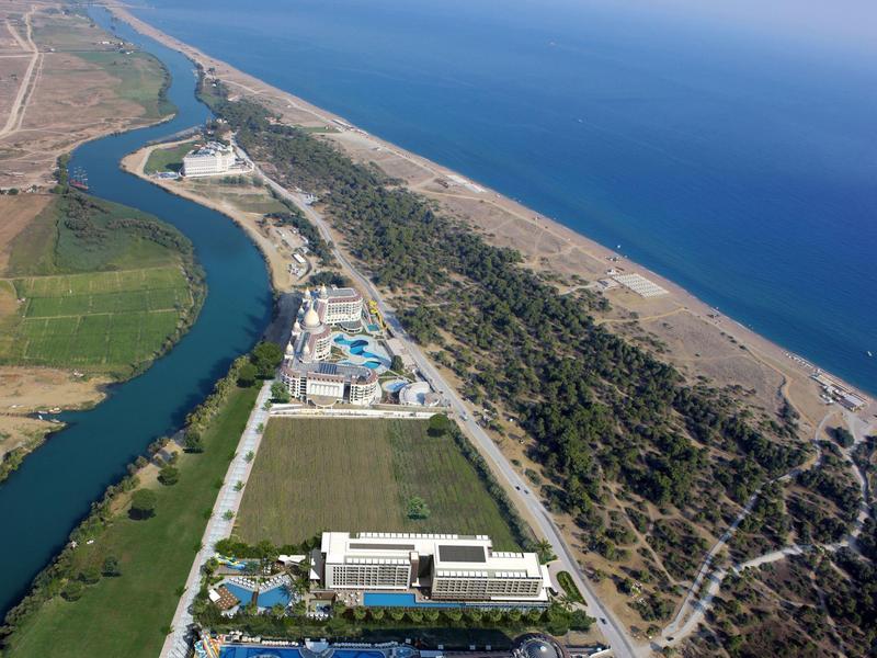 Letecký pohled na hotel mezi řekou a pláží podél pobřeží.