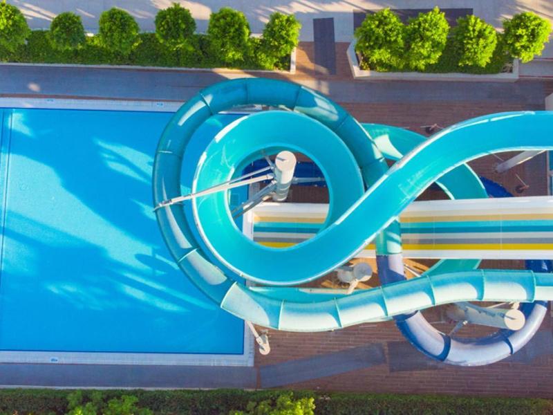 Letecký pohled na modrý bazén se dvěma modrými tobogány v hotelu.