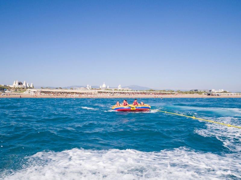 Velký hotel s bazénem, skluzavkou a slunečníky pod jasnou oblohou.