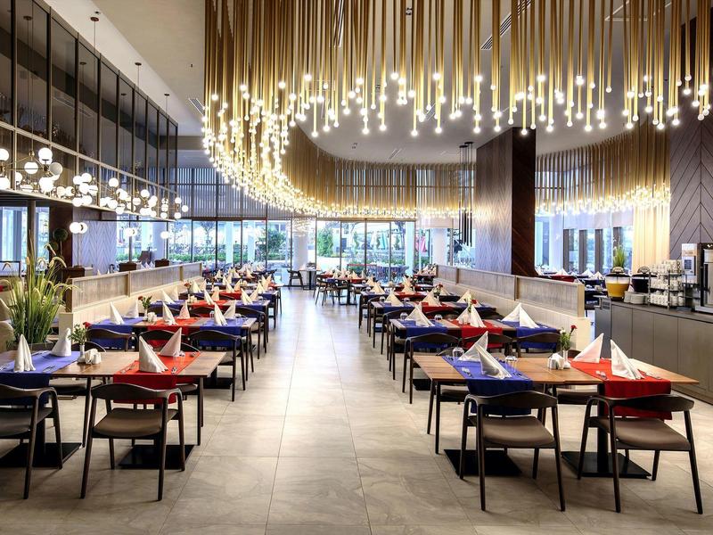 Moderní restaurace s dlouhým lustrem a elegantně prostřenými stoly.